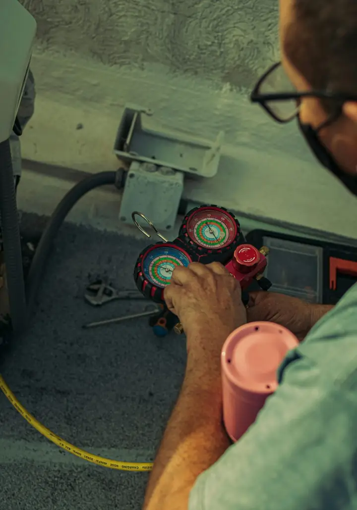 Technician connecting refrigerant gauges to an AC system